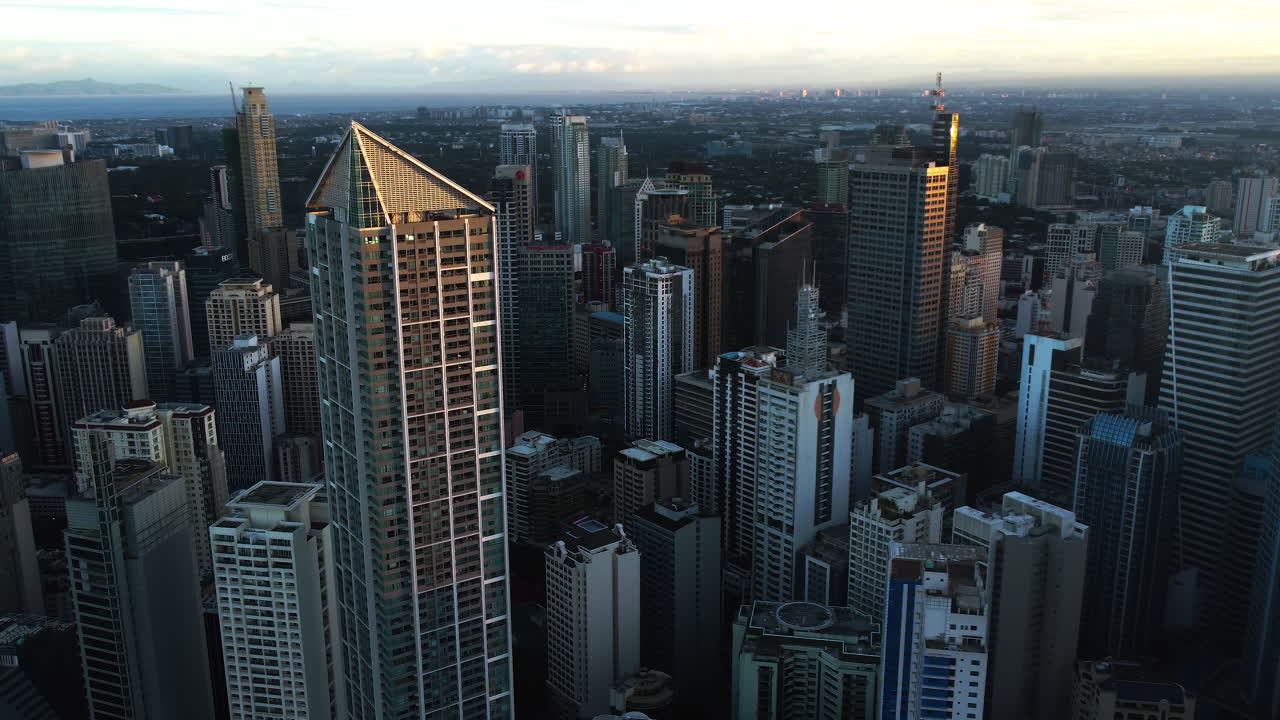 drone dando vueltas alrededor de un rascacielos iluminado por el sol de la ciudad de makati, por la noche en manila, filipinas