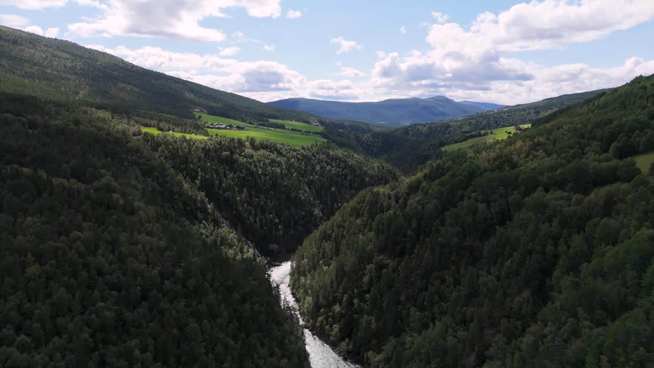 vista aérea de un valle de bosque exuberante con un río sinuoso, rodeado de colinas y cielos despejados