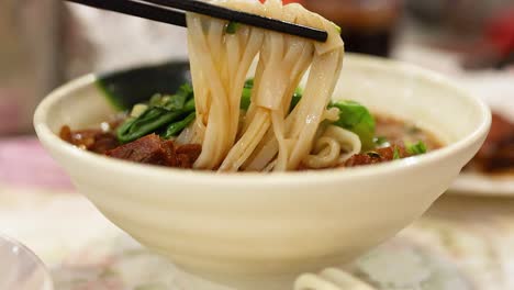 chopsticks lifting noodles from a bowl