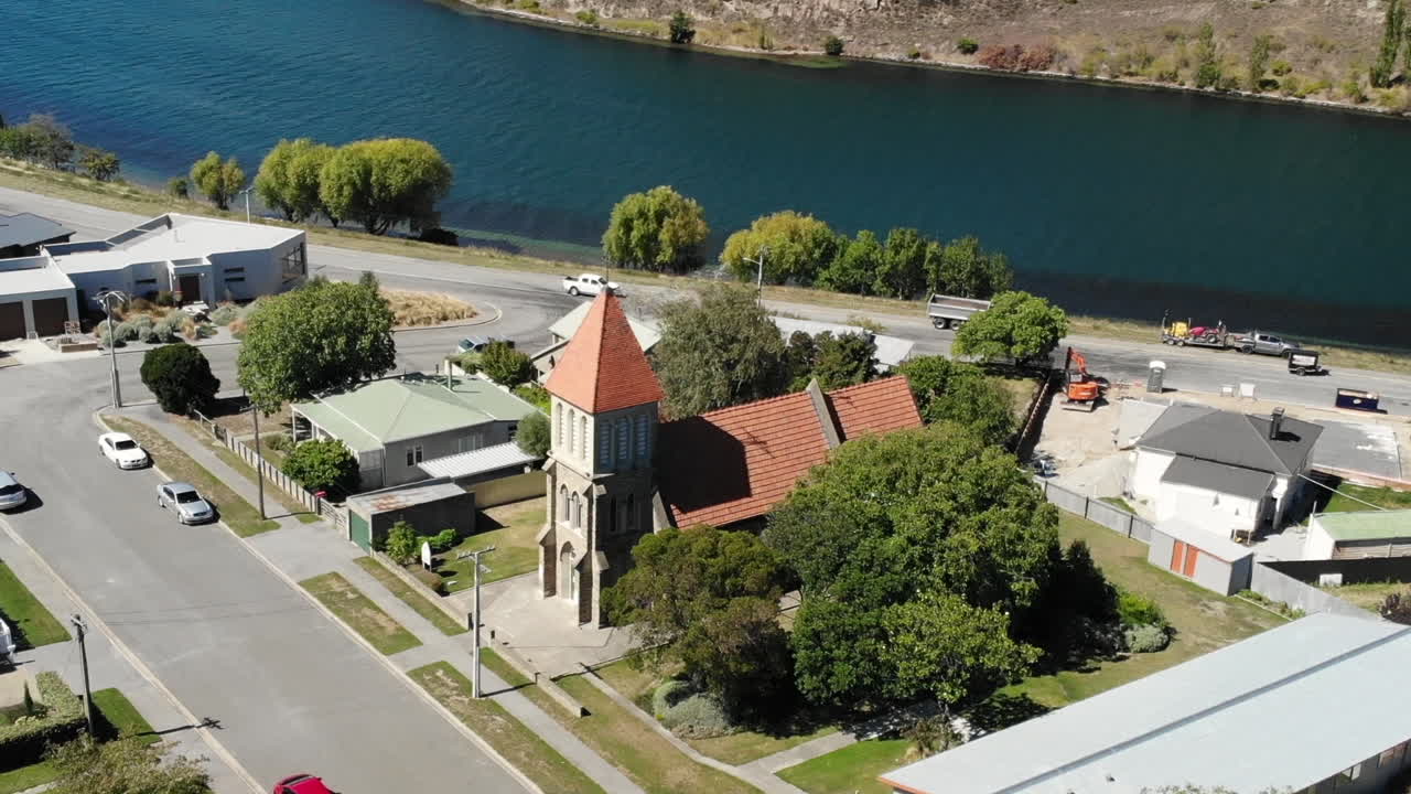 cromwell town, nueva zelanda, vista aérea de los mártires irlandeses, iglesia católica, río clutha en un día soleado, disparo de un dron en órbita