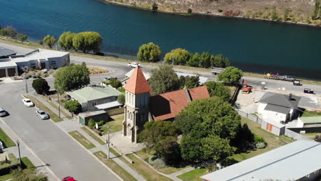 cromwell town, new zealand, aerial view of irish martyrs catholic church, clutha river on sunny day, orbit drone shot