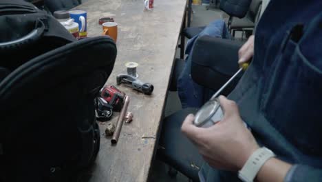 hombre abre una lata de pintura con un destornillador