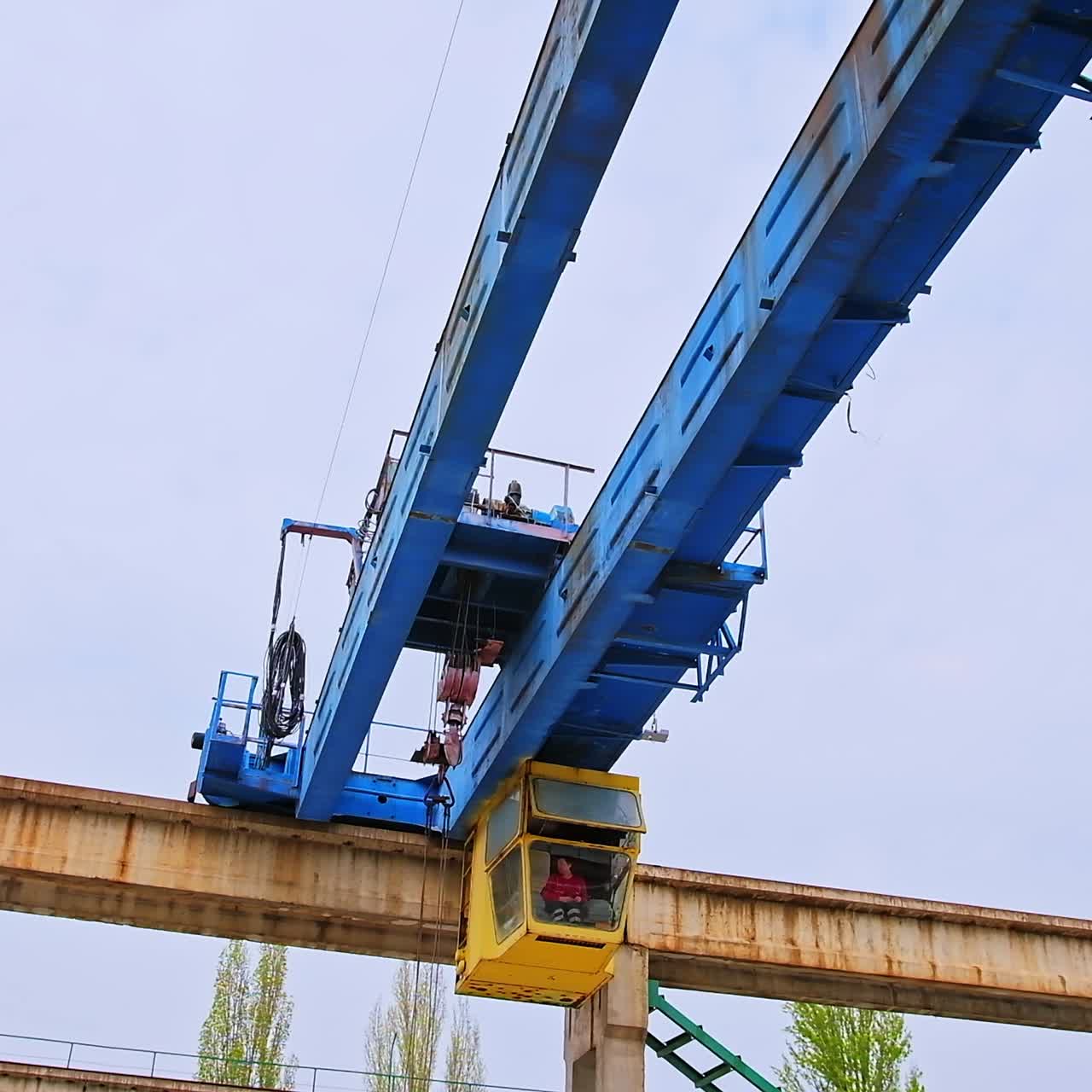 Automated crane machine for lifting and transporting materials. Worker sitting in the booth and operating the technique