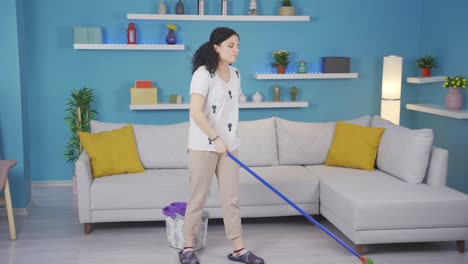 una joven pensativa limpia la casa.