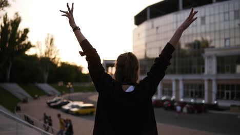 Seguimiento-De-Imágenes-Traseras-De-Una-Linda-Chica-Caminando-Por-La-Calle-Moderna.-Abre-Las-Manos-A-Los-Lados.-Sentirse-Libre.-Giro-Alrededor