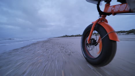 Mann,-Der-Am-Strand-Radelt,-Nahaufnahme-Eines-Orangefarbenen-Elektrofahrrads-In-Frankreich,-Occitanie