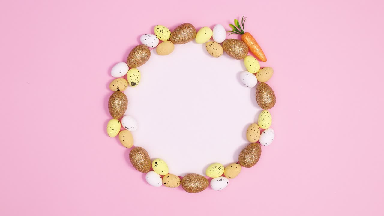 Trendy gold Easter eggs appear around paper card note on pastel pink background. Stop motion
