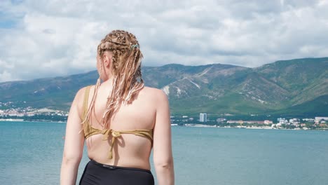 mujer en una playa con vistas al océano y las montañas