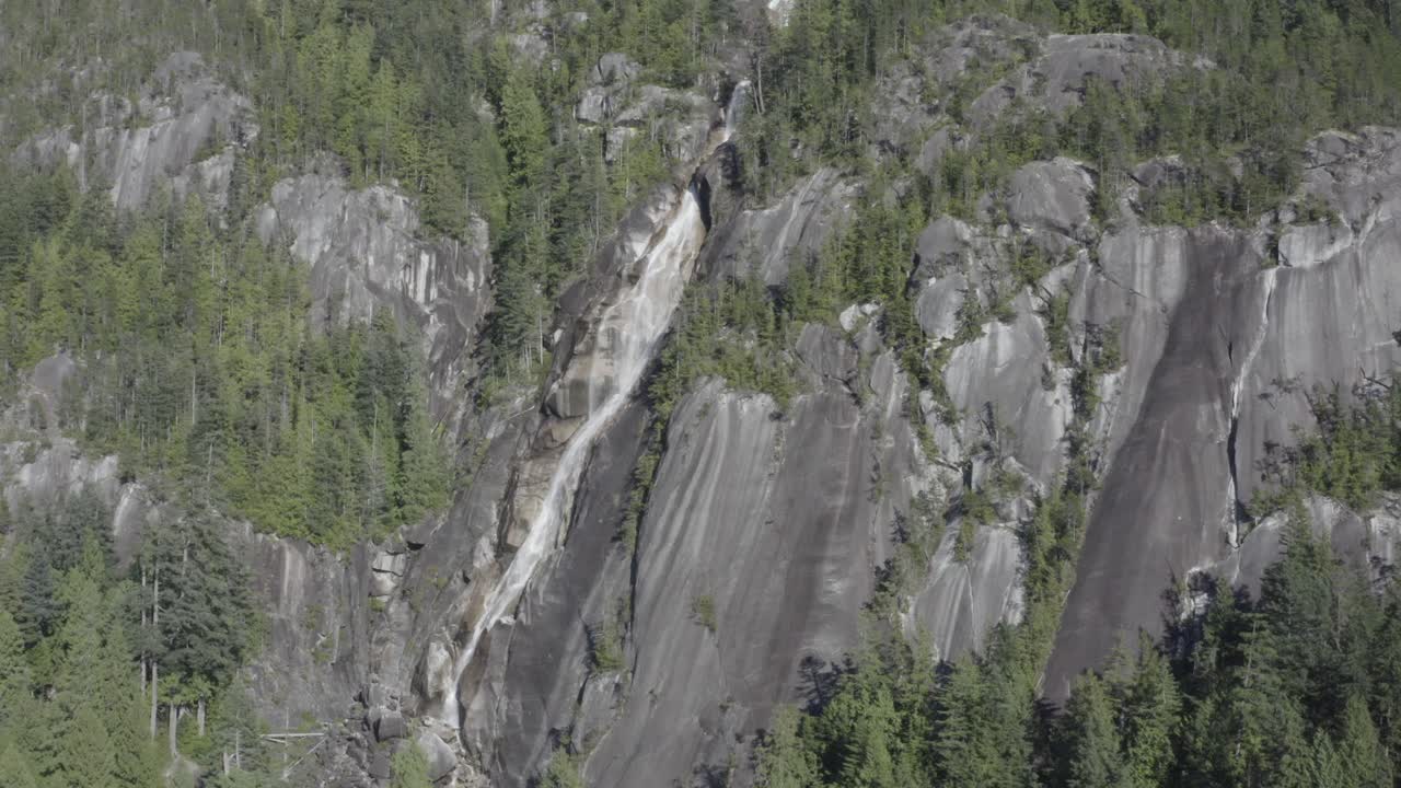 tranquilo impresionante impresionante toma aérea cerca de la ladera de la montaña de cascadas heladas que caen y los árboles cubiertos de acantilados de shannon falls bc squamish en el verano
