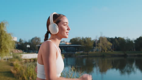 athletic fitness sport runner girl training putting on wireless headphones and jogging in park