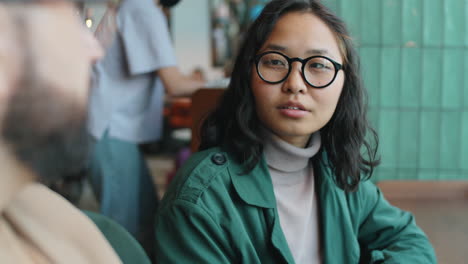asian woman talking with male colleague in cafe