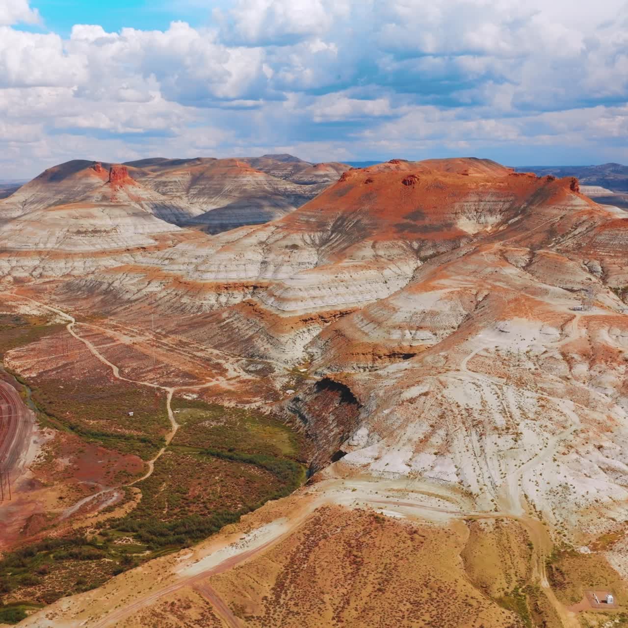 Fascinating mountainous scenery on sunny daytime. Railways with trains at the mountains foot. Cloudy sky at backdrop