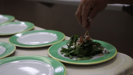 Hand-held-shot-of-a-chef-preparing-a-beautiful-salad-and-adding-finishing-touches