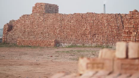 large stacks of bricks at a brickyard with a chimney in the background