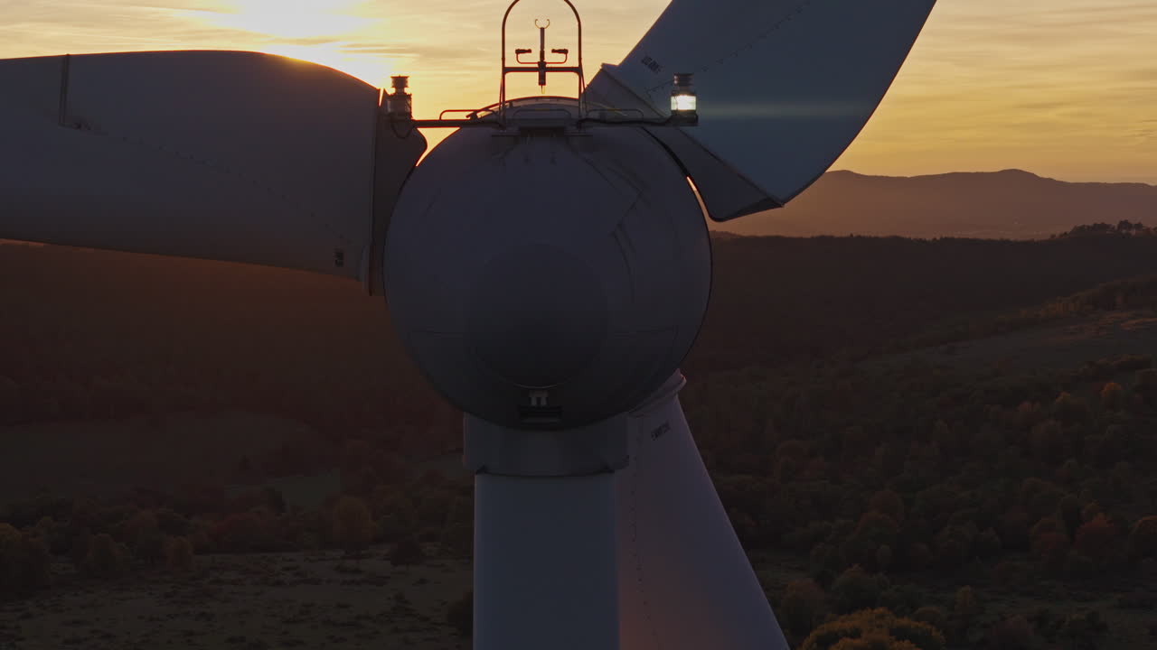Vindmøller står højt på en bakke under solnedgang, hvilket viser produktion af ren energi og overgangen.