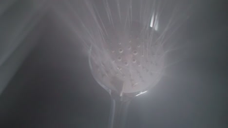 water pouring down from massage shower head in bathroom. liquid sprays and steam for body washing in home washroom bottom view. sanitary equipment