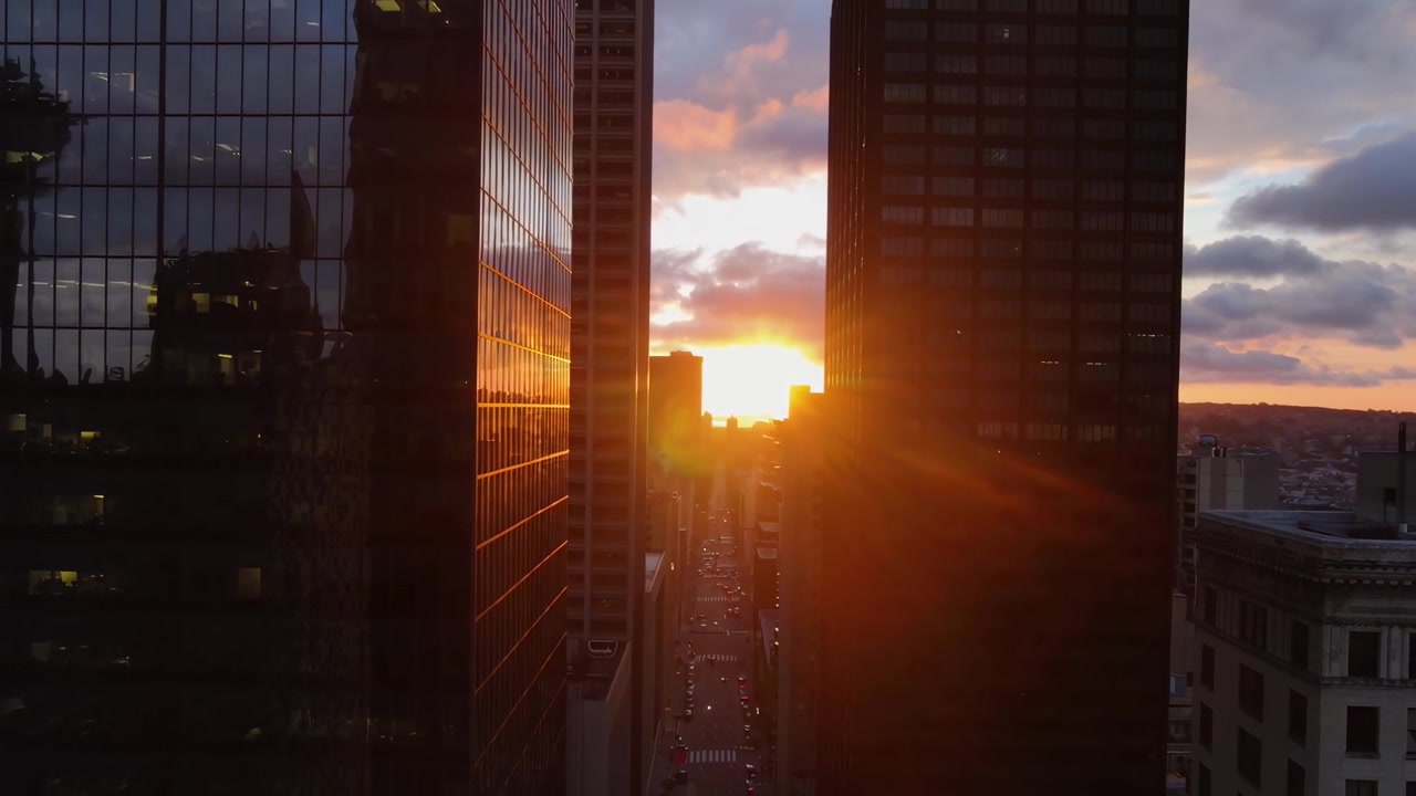 Pôr do sol com vista para uma rua movimentada da cidade entre arranha-céus