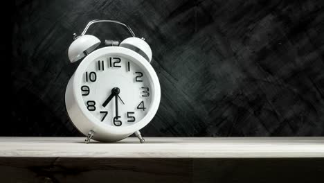 lapso de tiempo de un despertador vintage blanco en la mesa de madera con el fondo oscuro, tiempo de inicio 07:30 correr rápido a 07:45