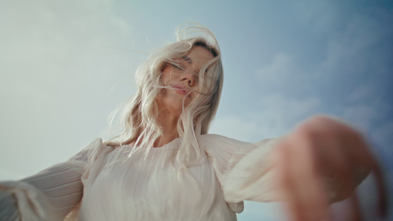 초상화 모델 여름 하늘은 빛으로 조명되었습니다. 여성은 카메라에 손을 흔들고 있습니다.