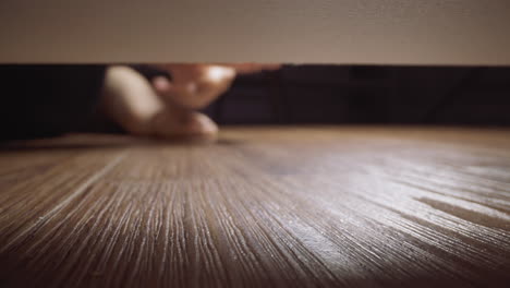 Woman-takes-gold-ring-rolled-under-sofa-on-wooden-floor