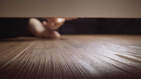 woman takes gold ring rolled under sofa on wooden floor