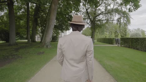 man in beige suit walking in a park