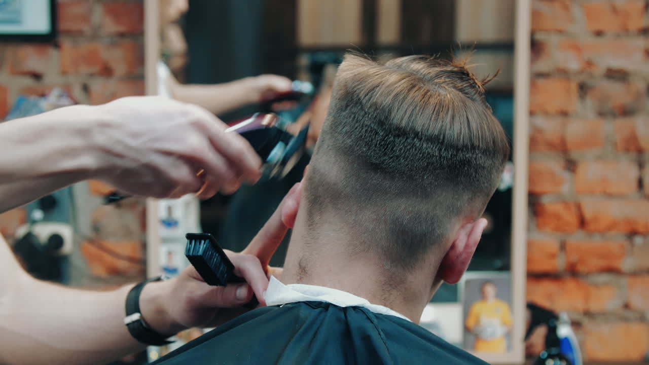 Parrucchiere che realizza un taglio corto al cliente. Barbiere che taglia capelli maschili con il tagliacapelli.