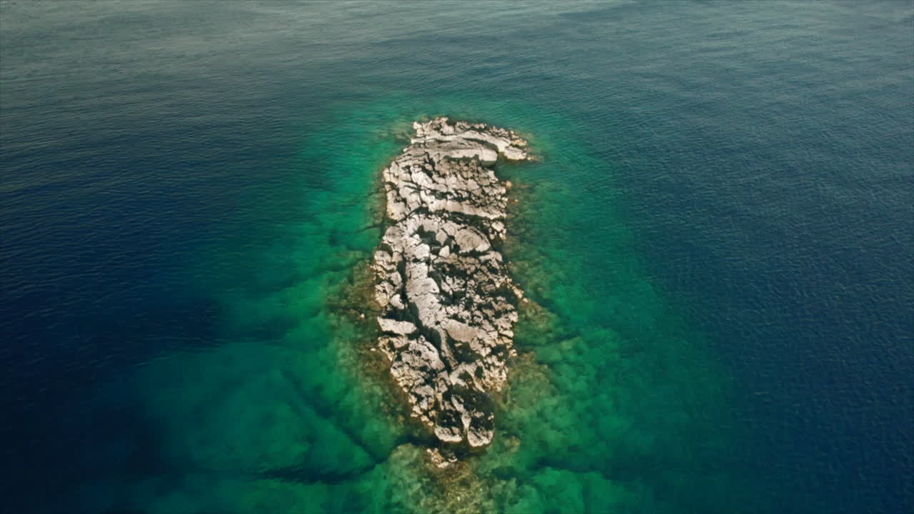Luftfoto af en klippeø i turkisblåt vand i det idylliske Ioniske Hav, Grækenland