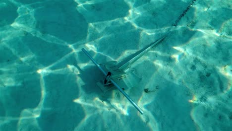 Danforth-anchor-secured-in-a-sand-bottom-with-light-shining-through-tropical-blue-water