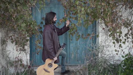 man with guitar by a blue door