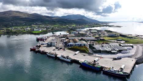 Paisaje-De-Drones-Del-Puerto-Pesquero-De-Castletownbere-En-West-Cork,-Irlanda,-Con-Montañas-Y-Ciudad-Al-Fondo-En-Una-Tranquila-Mañana-De-Verano