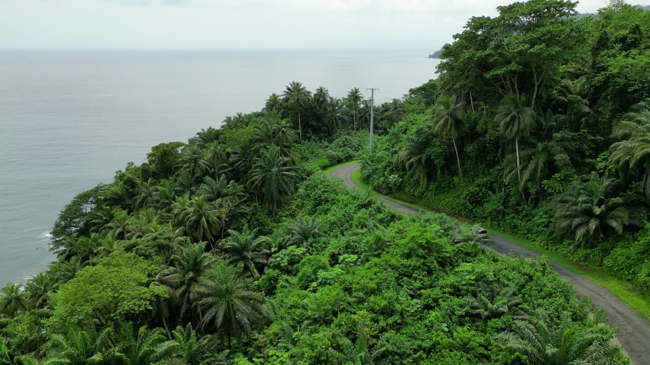 Panoramic drone shot following a car driving on the coastline of south Sao Tome