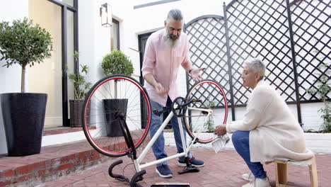 repairing bicycle together, senior couple enjoying outdoor activity in courtyard