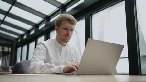 businessman is working with laptop in his modern office, sending emails by internet, busy and serious man is typing text