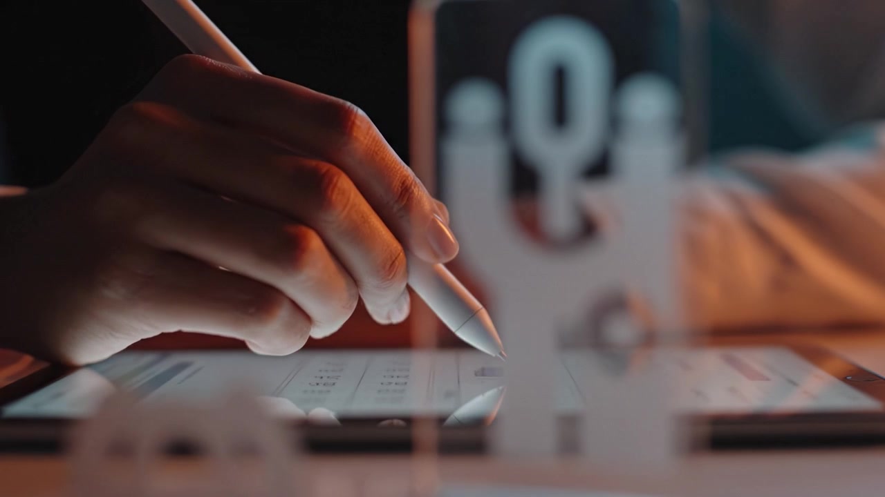 A focused hand using a stylus on a digital tablet, surrounded by abstract designs, showcasing creativity and digital artistry in a vibrant, modern workspace.