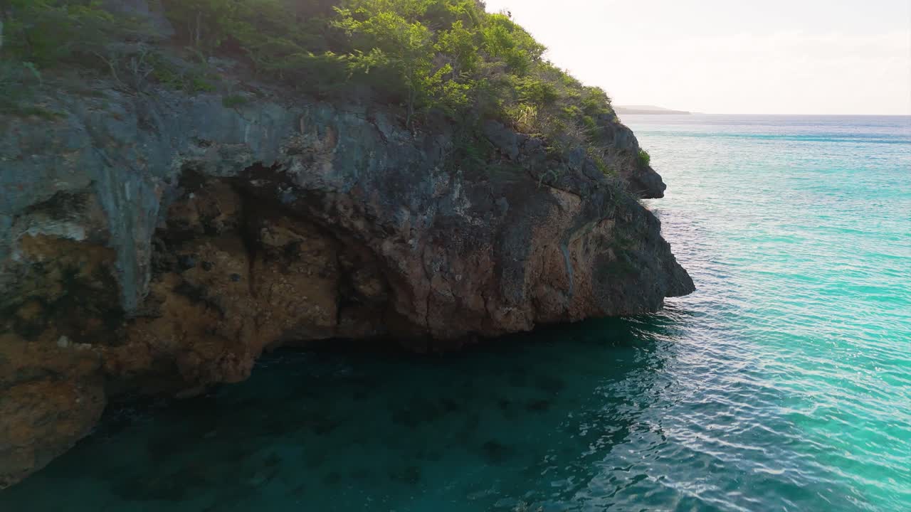 Acqua cristallina turchese e grotte lungo la costa di Westpunt, Curaçao, nei Caraibi all'alba