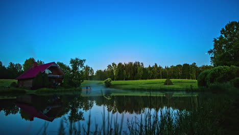 Dampf-Steigt-Aus-Dem-Warmen-Teichwasser-Bei-Einer-Hütte-Auf-Dem-Land,-Während-Der-Mond-Aufgeht---Zeitraffer