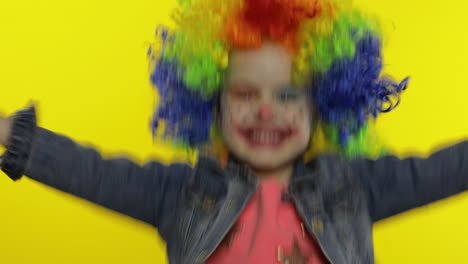 little child girl clown in wig making silly faces, having fun with money banknotes dollar cash