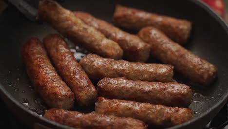 crop person turning homemade sausages frying in pan