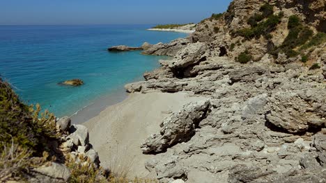 secret beach isolated by cliffs, white sand washed by turquoise sea water on summer vacation in mediterranean