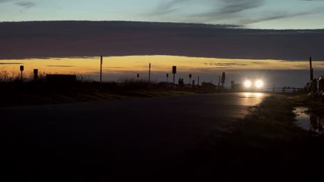 Dark-after-sunset,-cars-and-people-passing-by