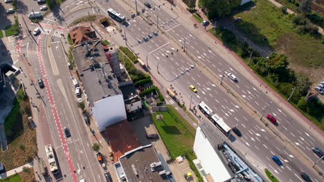 Aerial-bird's-eye-view-above-street-intersection-in-Gdynia-Poland,-public-transport-buses-and-cars-drive-at-midday