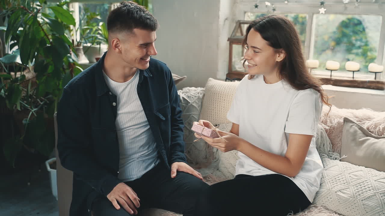 젊은 남자가 그의 여자친구에게 깜짝 선물을 주고 그들은 포옹한다