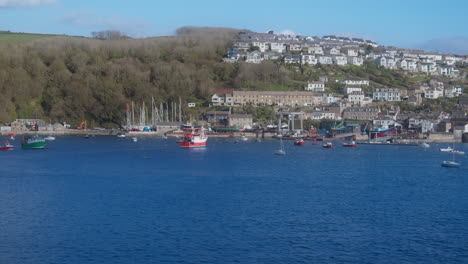 view across from fowey a fishing trawler boat enters polruan coastal village working harbour cornwall, england - wide shot