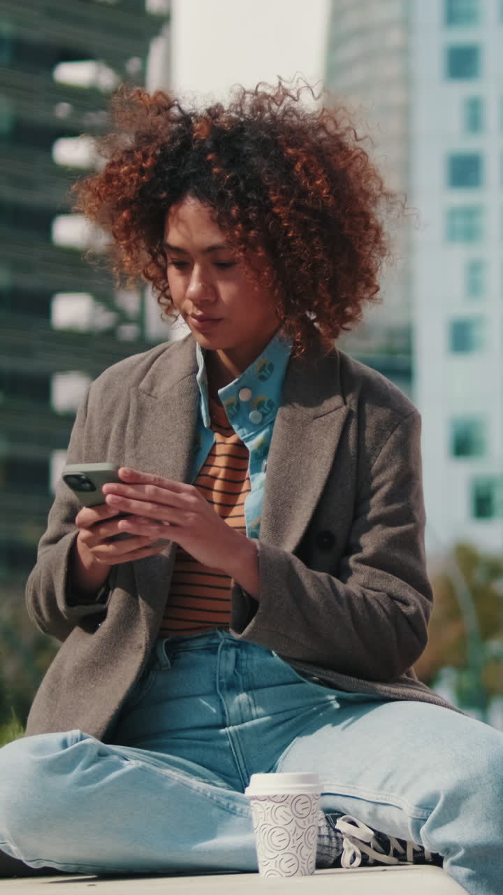 Young Woman Using Smartphone in City Park