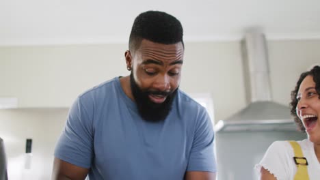 smiling diverse female and male friends cooking and talking in kitchen, in slow motion