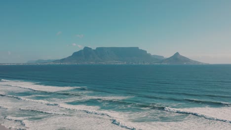 immerse yourself in scenic footage of serene waves gently rolling across vast seascape in canada, framed by majestic mountains under clear blue sky during daytime