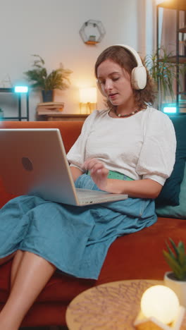 feliz relajado muy feliz mujer joven caucásica en auriculares inalámbricos escuchando música sentada en el sofá