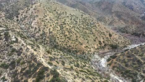 Aerial-dolly-and-tilt-down-over-a-trail-in-Deep-Creek,Hesperia-Desert-in-California,-USA-during-daytime