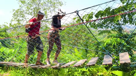 couple enjoying a rope bridge adventure in a tropical forest